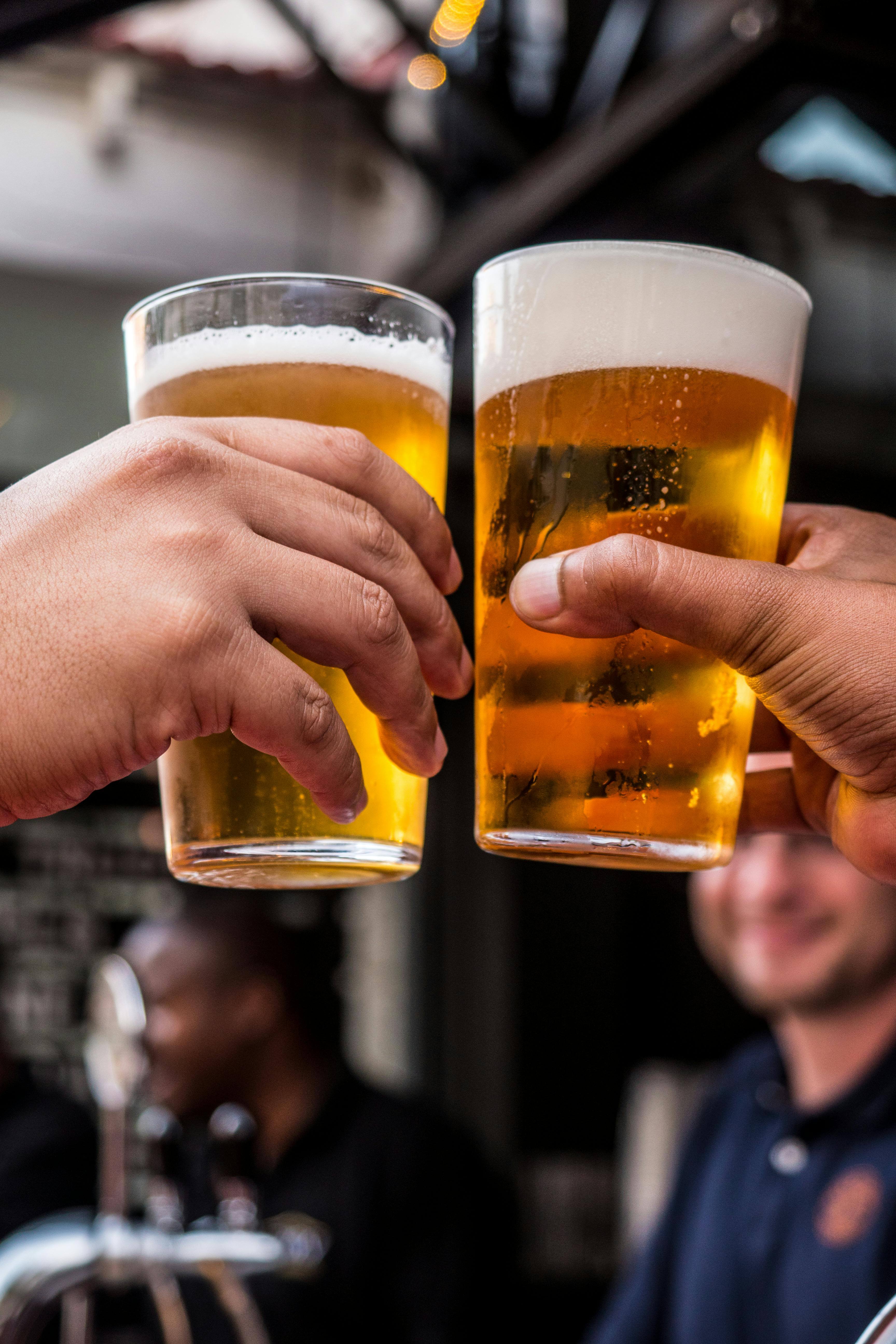 men holding two glasses of beer