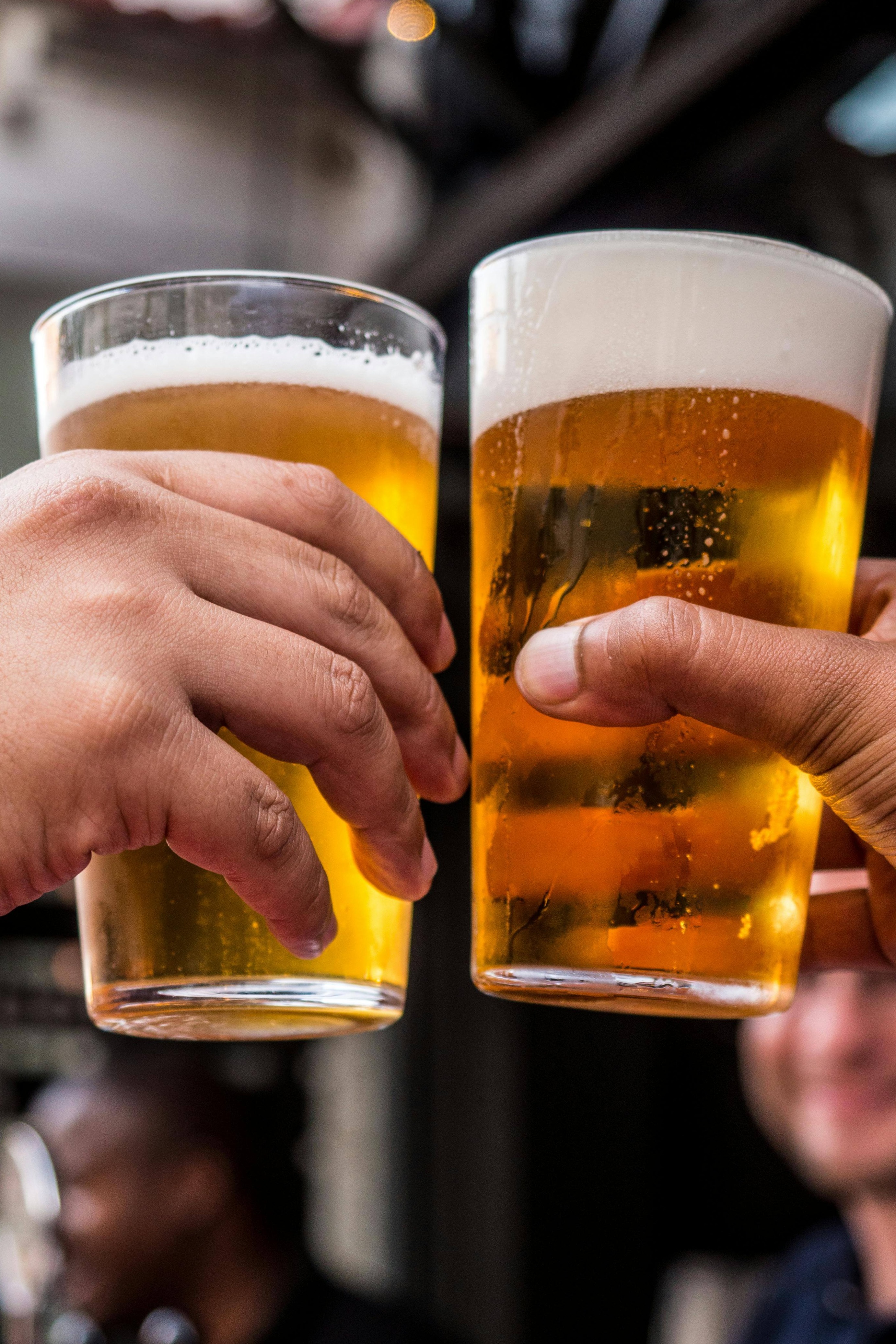 men holding two glasses of beer