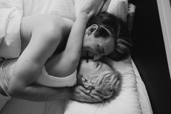 an escort and her client hugging in bed smiling