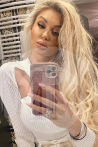 London escort Alexia taking a selfie in a white dress