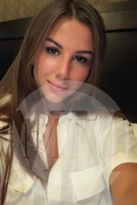 Crystal taking a selfie in a white shirt with a soft smile.