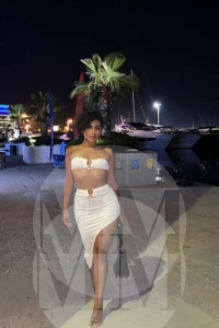 Madrid escort India wearing a white dress at a bar