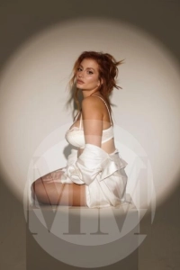 London escort Juliet kneeling on the floor wearing a white bra and skirt
