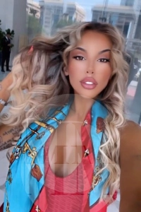 London escort Lia wearing a red dress and blue scarf