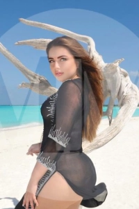 Dubai escort Maddie stood on a beach wearing a black see through dress