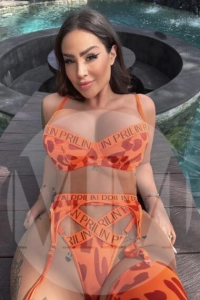 Dubai escort Mina lay on a chair wearing an orange bikini