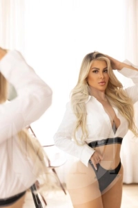 London escort Zaya wearing a white top and black panties