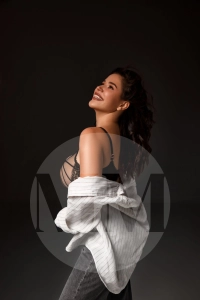 Arianna slipping down a white shirt revealing her strappy lingerie, she has a wide smile. 